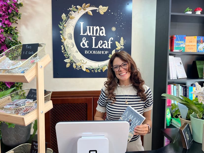 La librera de Luna & Leaf en el mostrador con un libro en la mano