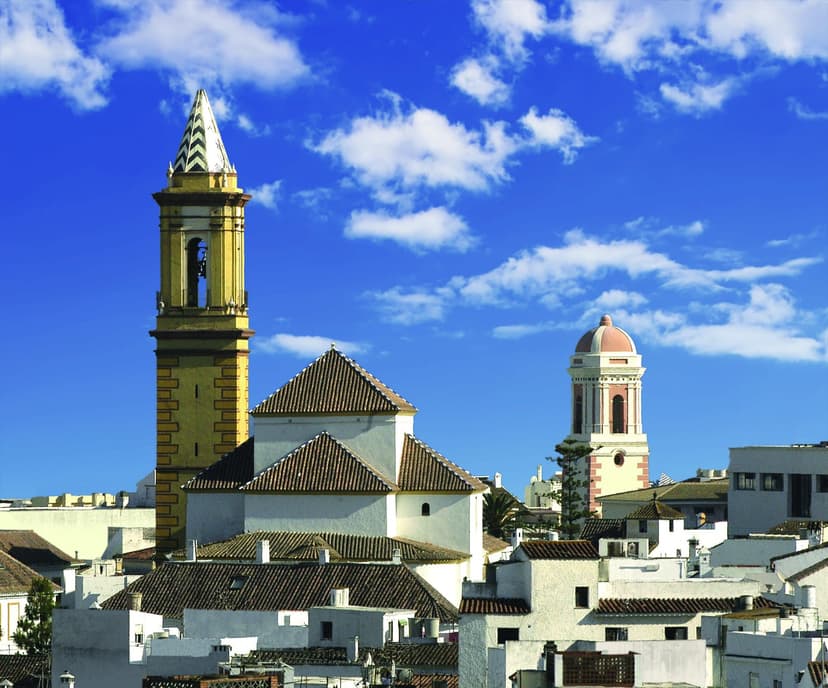 Sobre los tejados del casco antiguo de Estepona, la torre de la Iglesia de los Remedios a la izquierda y, al fondo a la derecha, la Torre del Reloj: dos torres de dos edificios distintos
